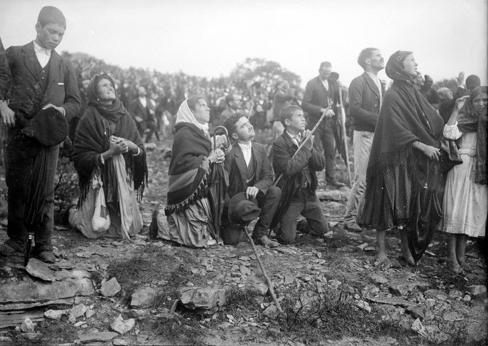 Multid&atilde;o de romeiros, alguns ajoelhados, de rosto voltado para o c&eacute;u na Cova da Iria, em Fátima, em 13 de outubro de 1917