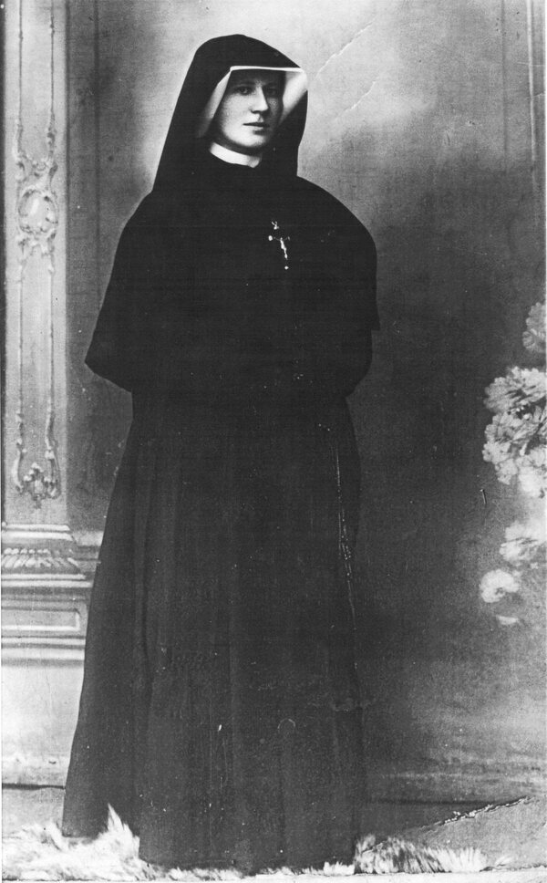 Fotografia de Santa Faustina Kowalska com o h&aacute;bito das Irm&atilde;s de Nossa Senhora da Miseric&oacute;rdia, de p&eacute;, com um pequeno crucifixo ao peito
